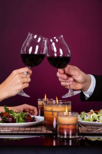 Smiling Couple Tossing Wine Glass While Having Dinner